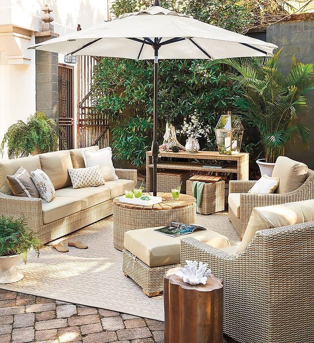 an outdoor living area with wicker furniture and white umbrella over the couches,