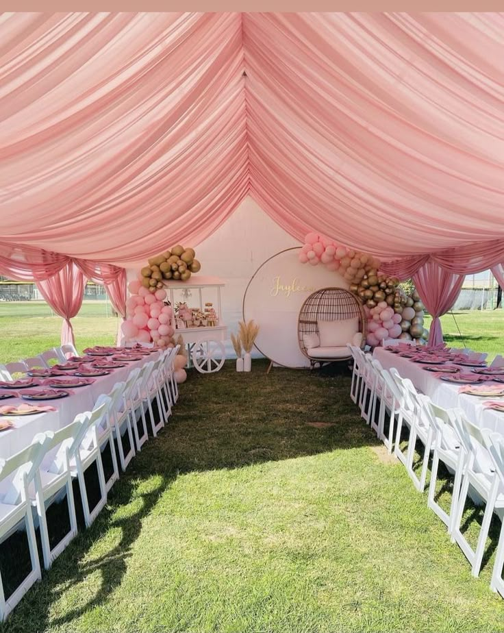 an outdoor tent set up for a party with pink and white decorations on the tables