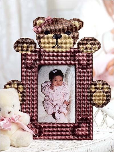 a teddy bear sitting next to a frame with a baby's picture on it