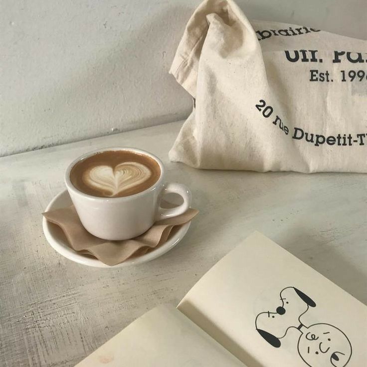 a cup of coffee sitting on top of a saucer next to an open book