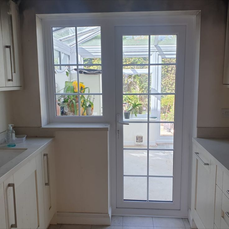 an open door leading to a kitchen with white cabinets and counter tops on both sides