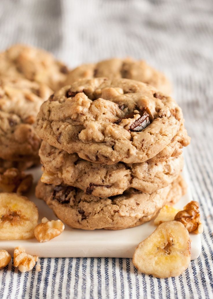 three cookies stacked on top of each other with bananas and walnuts next to them