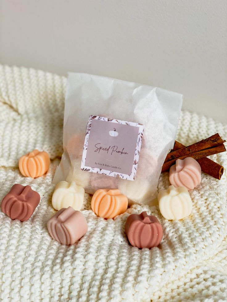 a bag filled with candy sitting on top of a white knitted blanket next to cinnamon sticks