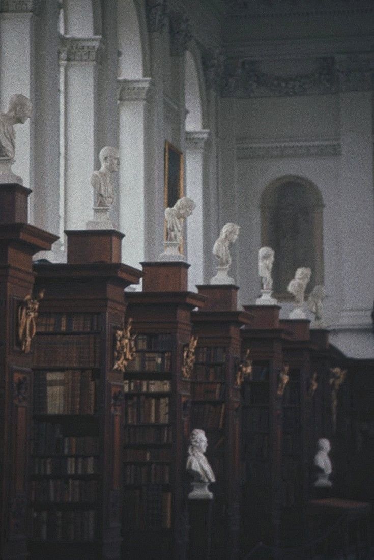 many bookshelves with statues on them in a room