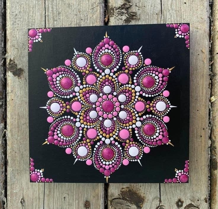 a painting on wood with pink and white dots in the center, surrounded by beads