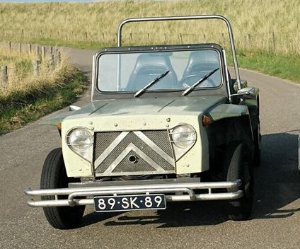 an old jeep is parked on the side of the road next to a trailer with two people in it