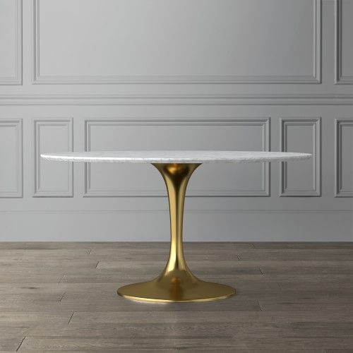 a white marble table with gold pedestals in front of a gray wall and wooden floor