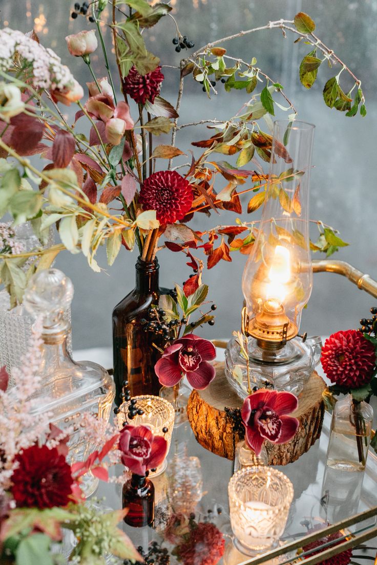 an arrangement of flowers and candles on a table