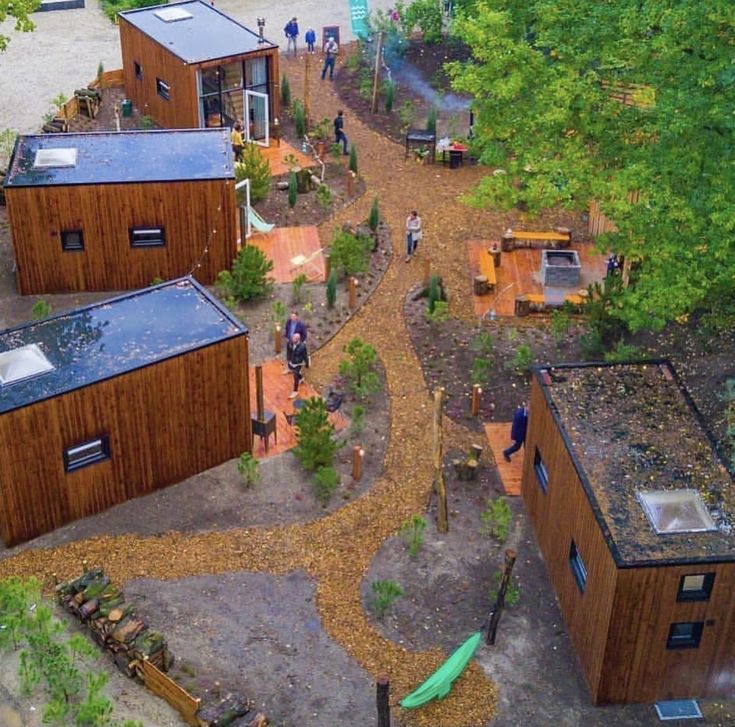 an aerial view of several wooden buildings and people walking in the woods near them,