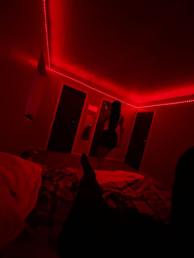 a person is sitting on a bed in the dark with red light coming from their head