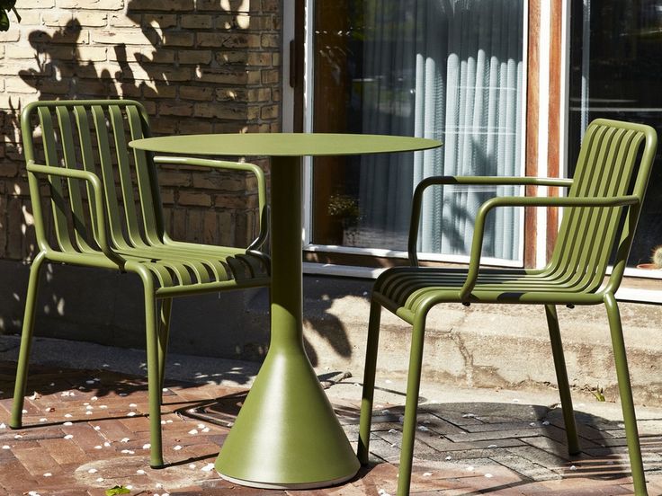 two green plastic chairs and a table outside