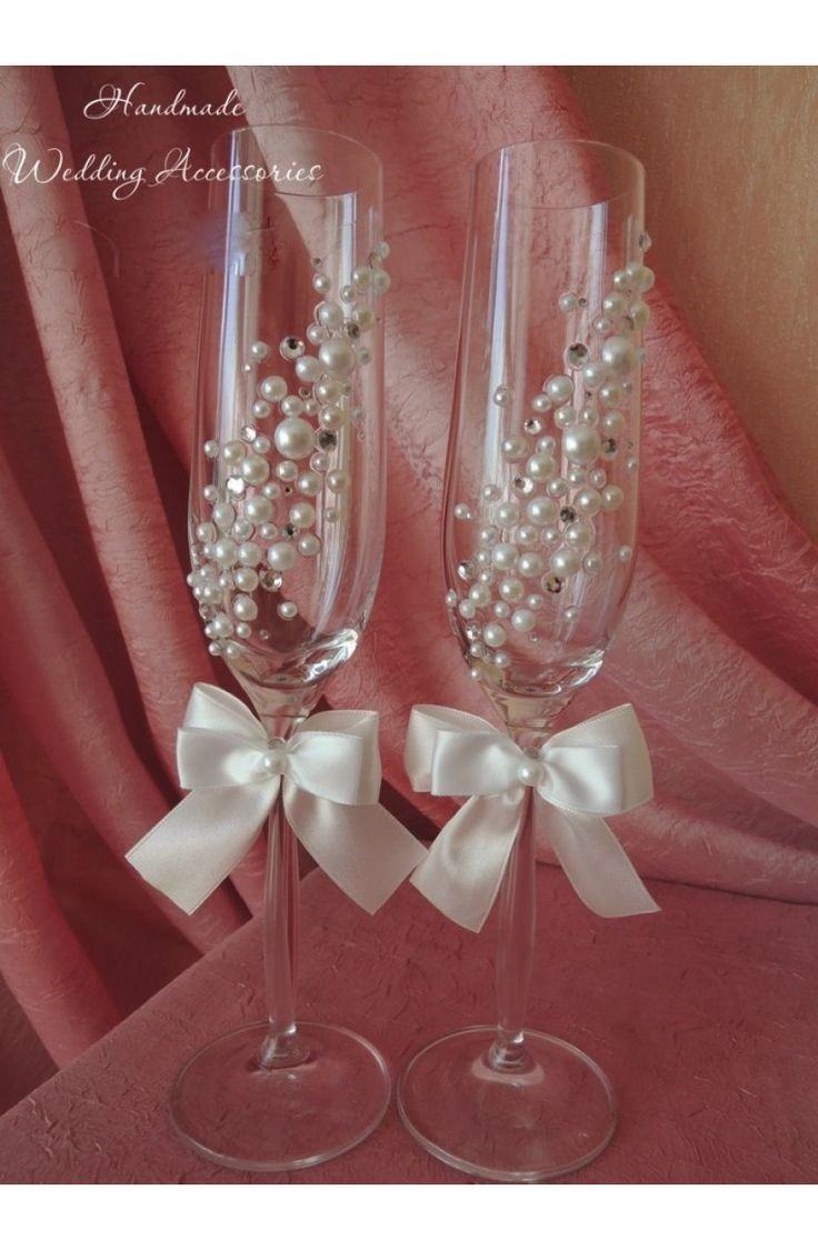 two wine glasses with pearls and bows on them