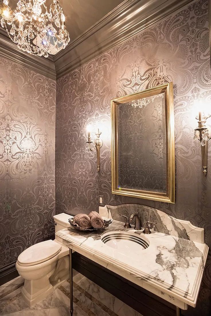 a fancy bathroom with marble counter tops and wall papered walls, along with a chandelier