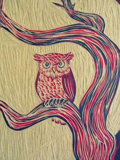 an owl sitting on top of a tree branch with red and blue swirls in the branches