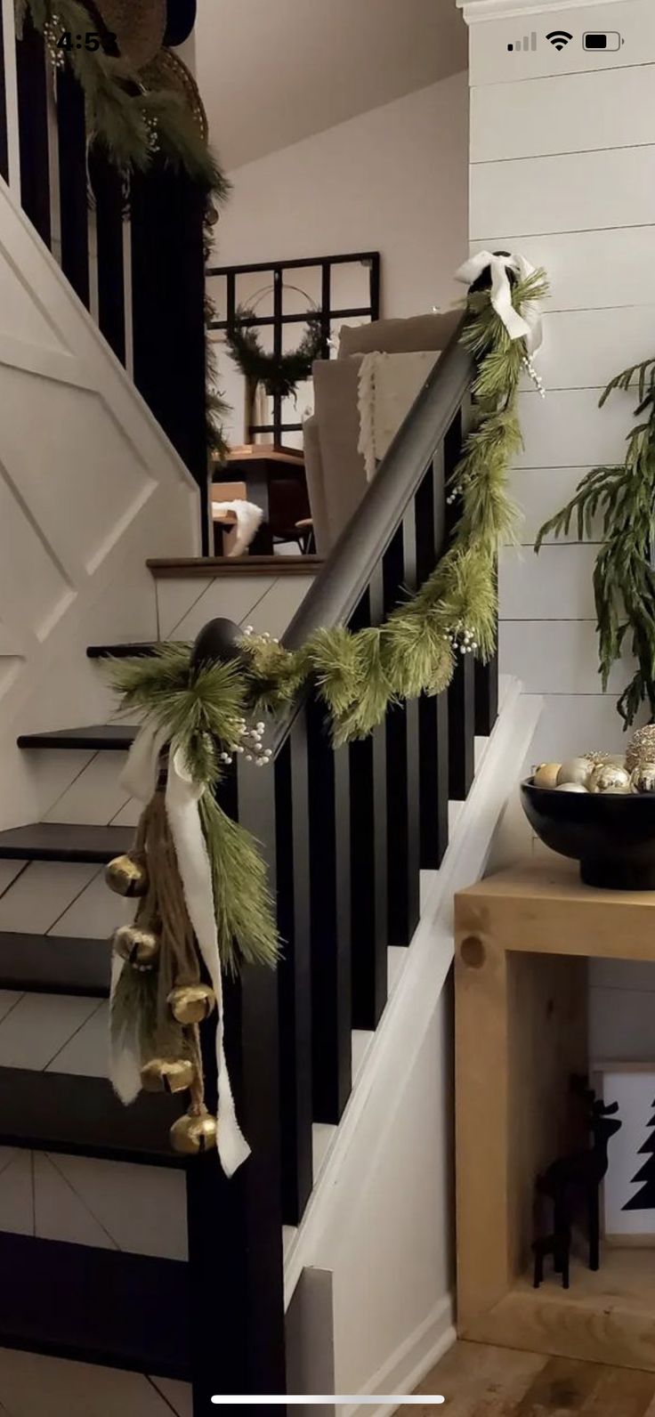 christmas garland hanging on the banister and stair railing in a home decorated with greenery