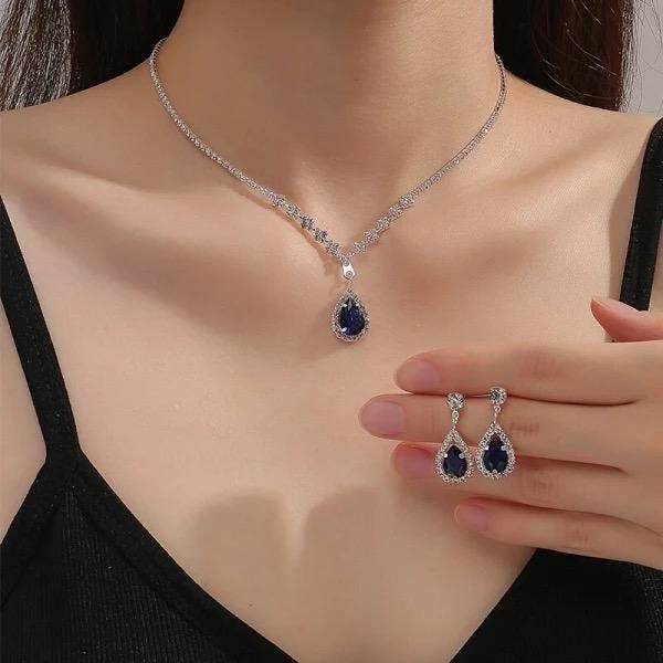 This stunning jewelry set includes a teardrop-shaped necklace and matching earrings, both adorned with deep blue sapphire cubic zirconia stones. The necklace is designed with a delicate silver-plated chain that gracefully enhances the beauty of the blue teardrop pendant. Paired with the matching earrings, this set is perfect for adding a touch of elegance to any formal occasion or as a thoughtful gift for someone special. Whether worn at weddings, evening galas, or celebrations, this set will ma Blue Jewel Necklaces, Midnight Blue Jewelry, Selena Gomez Jewelry, Fancy Jewelry Set, Royal Jewelry Aesthetic, Blue Jewelry Aesthetic, Royal Necklaces, Blue And Silver Jewelry, Blue Jewlery