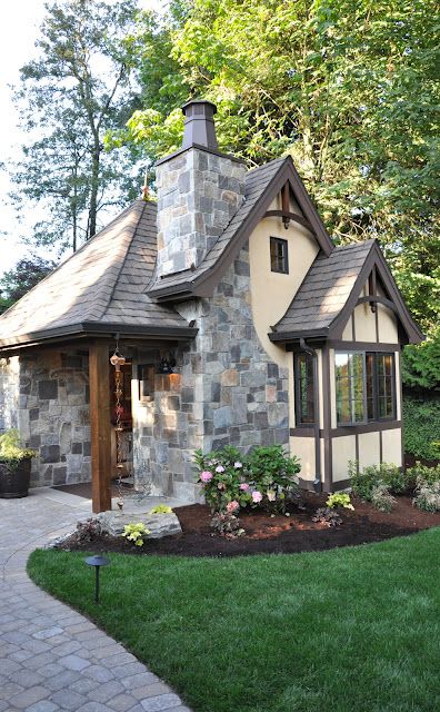 a small stone house in the middle of a yard