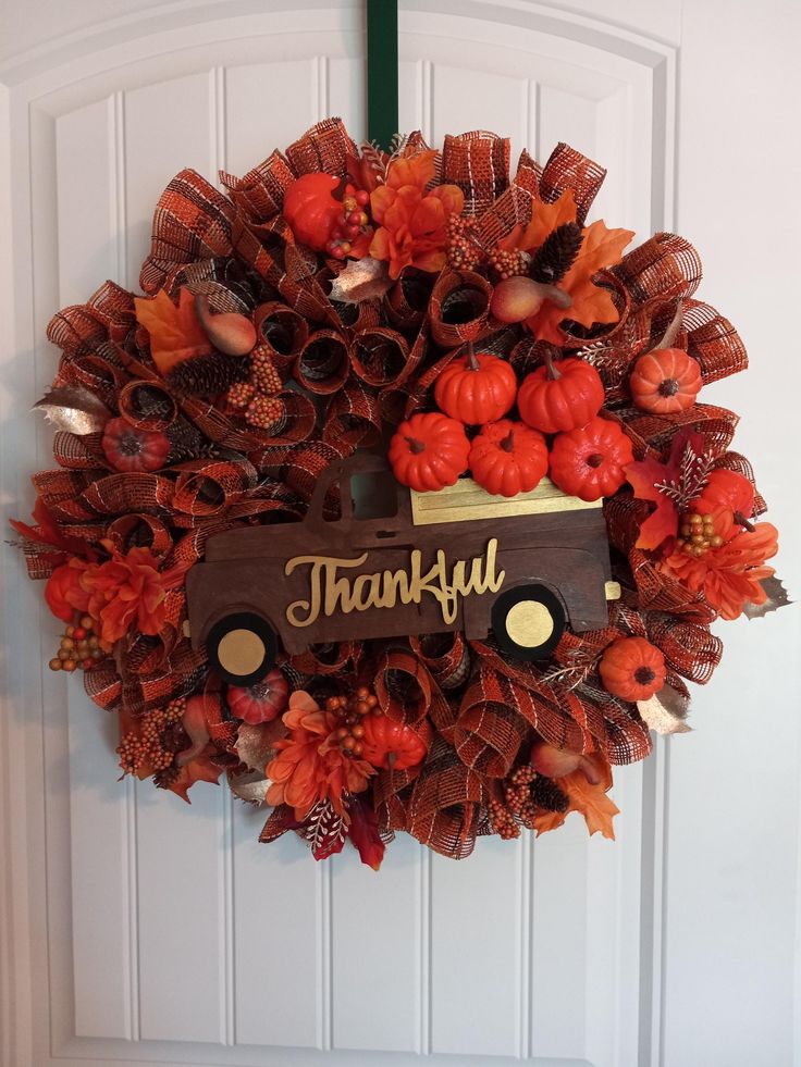 a wreath with a truck and pumpkins hanging on the front door to say, thank you