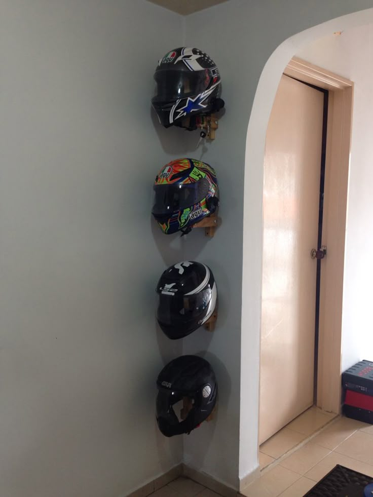 several helmets are hanging on the wall next to a door in a room with tile flooring