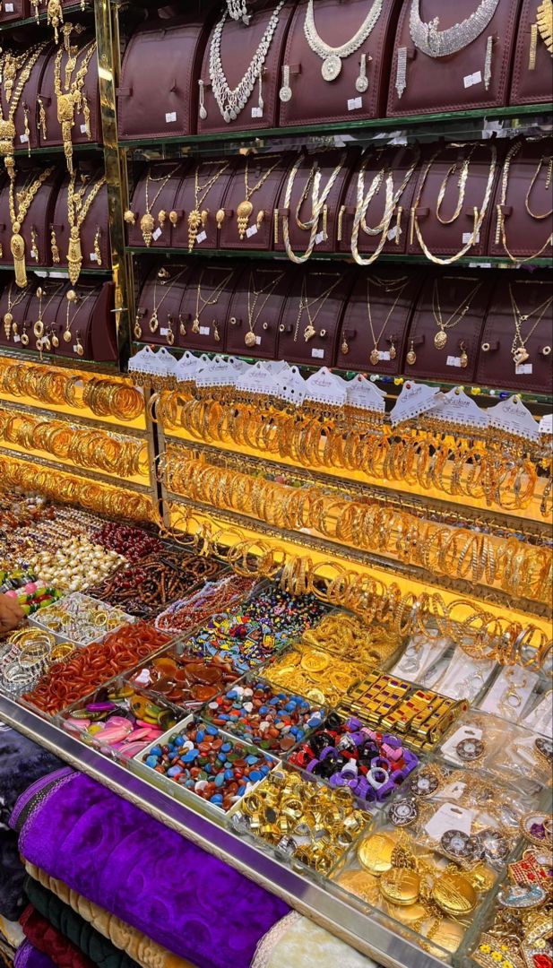 many necklaces and bracelets are on display in a store with lots of gold jewelry