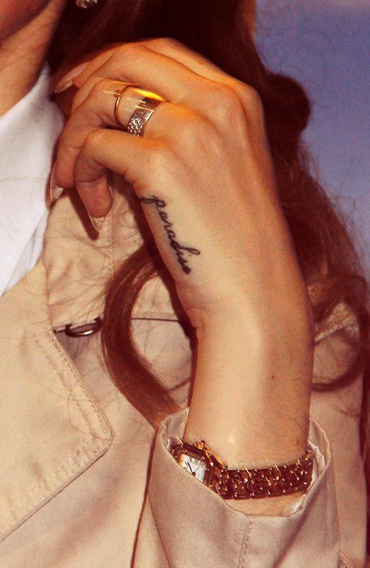 a woman in a trench coat holding her hand up to her ear with the word love written on it