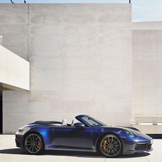 a blue porsche sports car parked in front of a building with concrete floors and walls