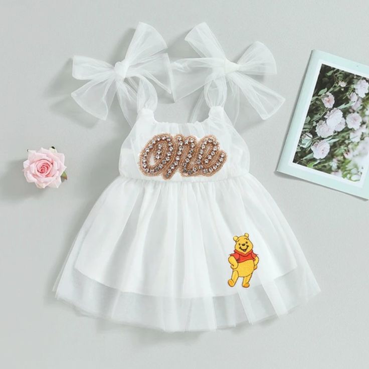 a white dress with the word pooh on it next to flowers and a photo