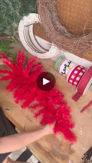 a person is making some red feathers on a table