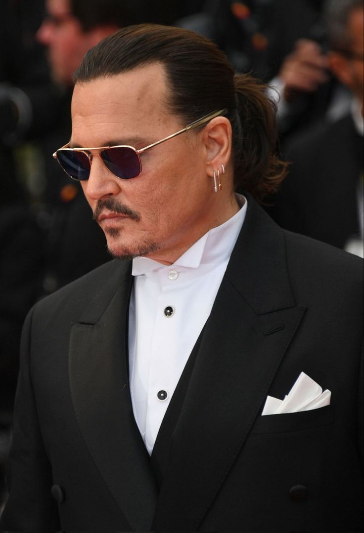 johnny depple wearing sunglasses and a black tuxedo at the red carpet