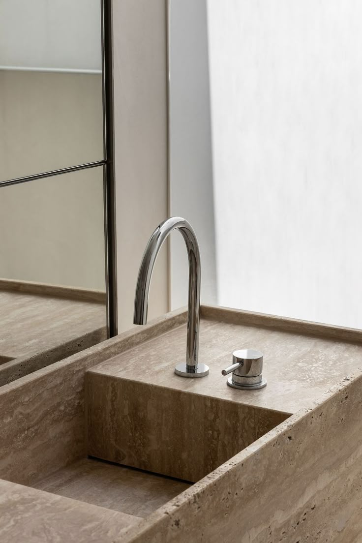 a bathroom sink with a faucet in the middle and a mirror behind it