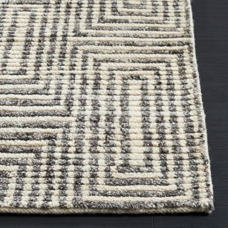 an area rug with grey and white squares on the top, in front of a black floor