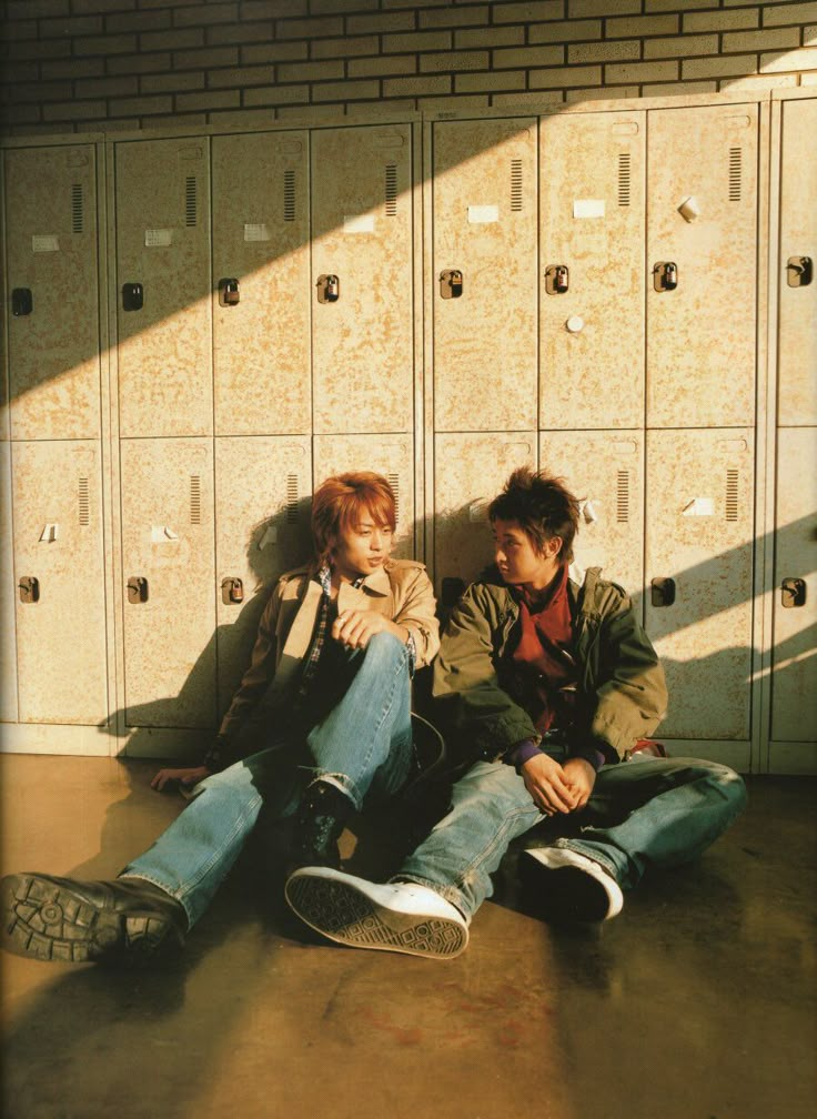 two people sitting on the ground in front of lockers