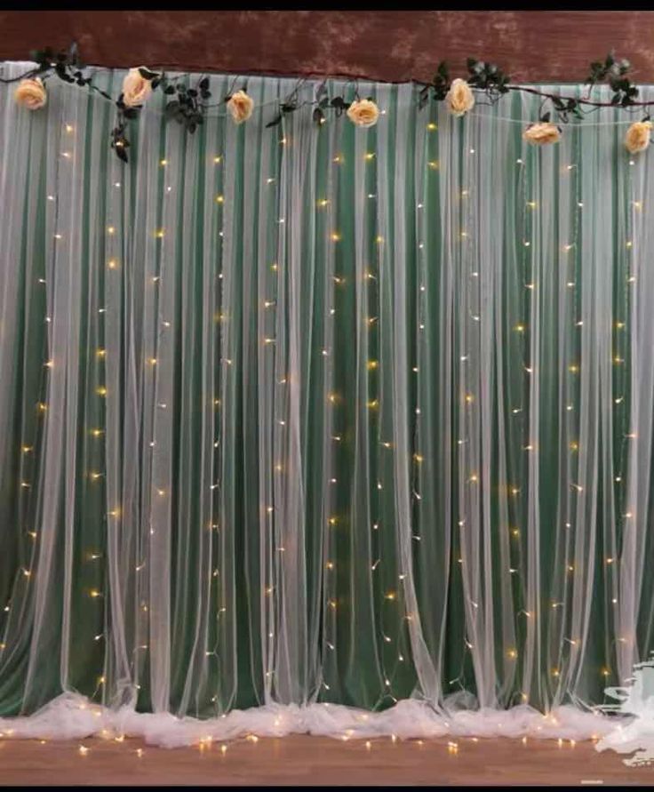 the wedding backdrop is decorated with flowers and lights in shades of green, white and gold