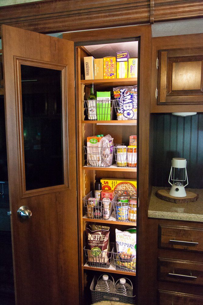 an open pantry door in a kitchen with lots of food on the shelves and baskets