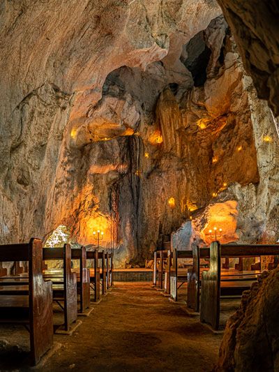 the inside of a cave with benches and lights