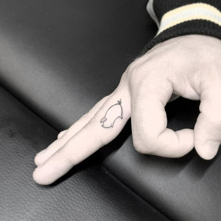 a person's hand with a small heart tattoo on it, resting on a leather surface