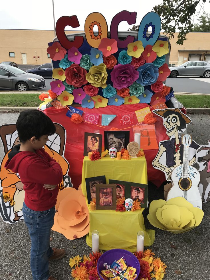 a young boy standing in front of a table with flowers and pictures on it,