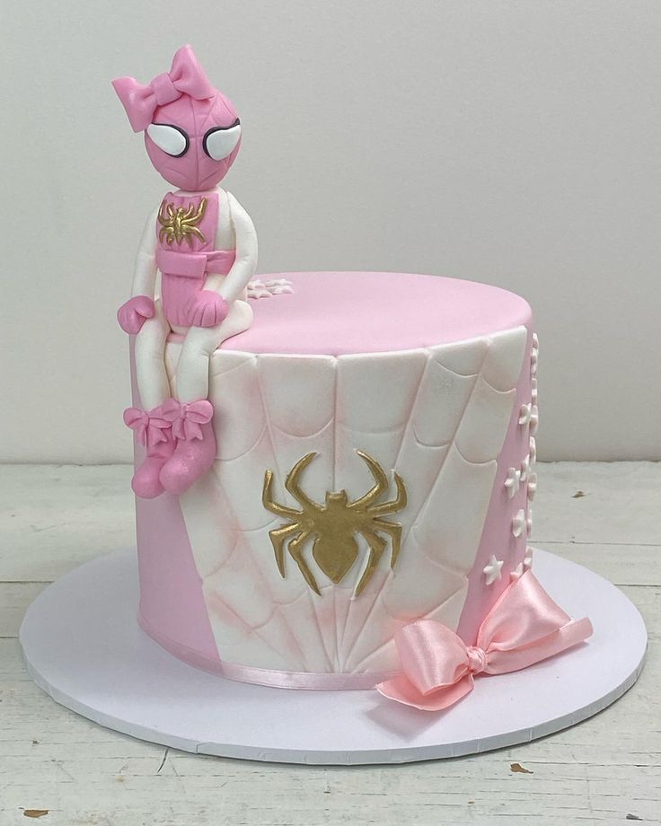 a pink and white cake with a spider on top