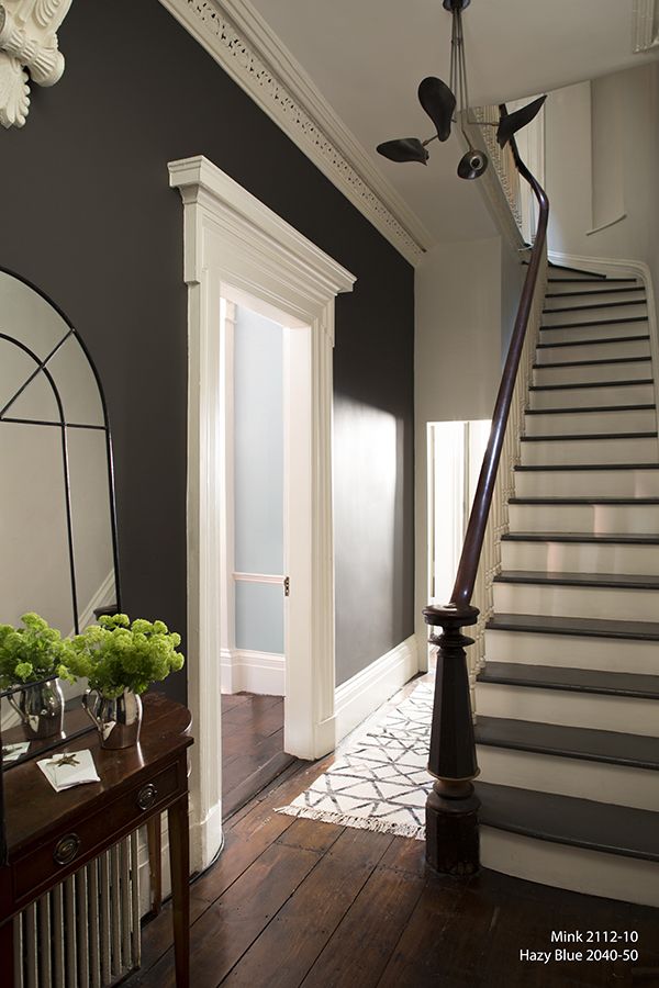 a staircase leading up to a foyer with flowers on the table and vases next to it