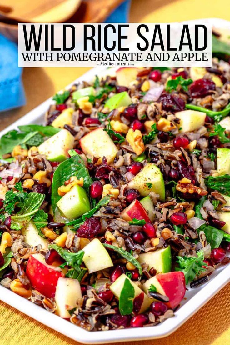 wild rice salad with pomegranate and apple in a white dish on a yellow tablecloth