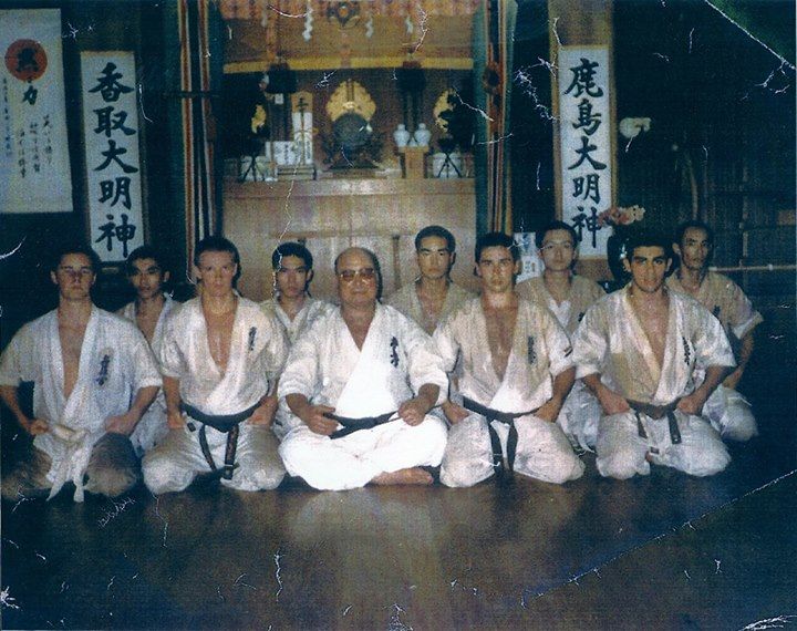 a group of men sitting in front of each other on top of a wooden floor