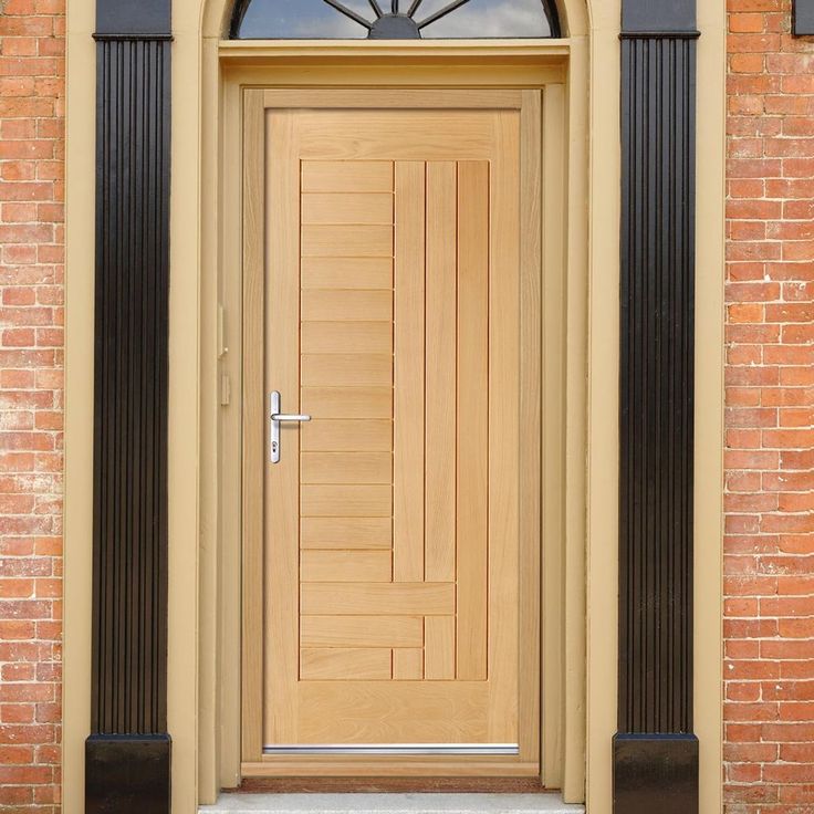 a wooden door on the side of a brick building with an arched glass window above it