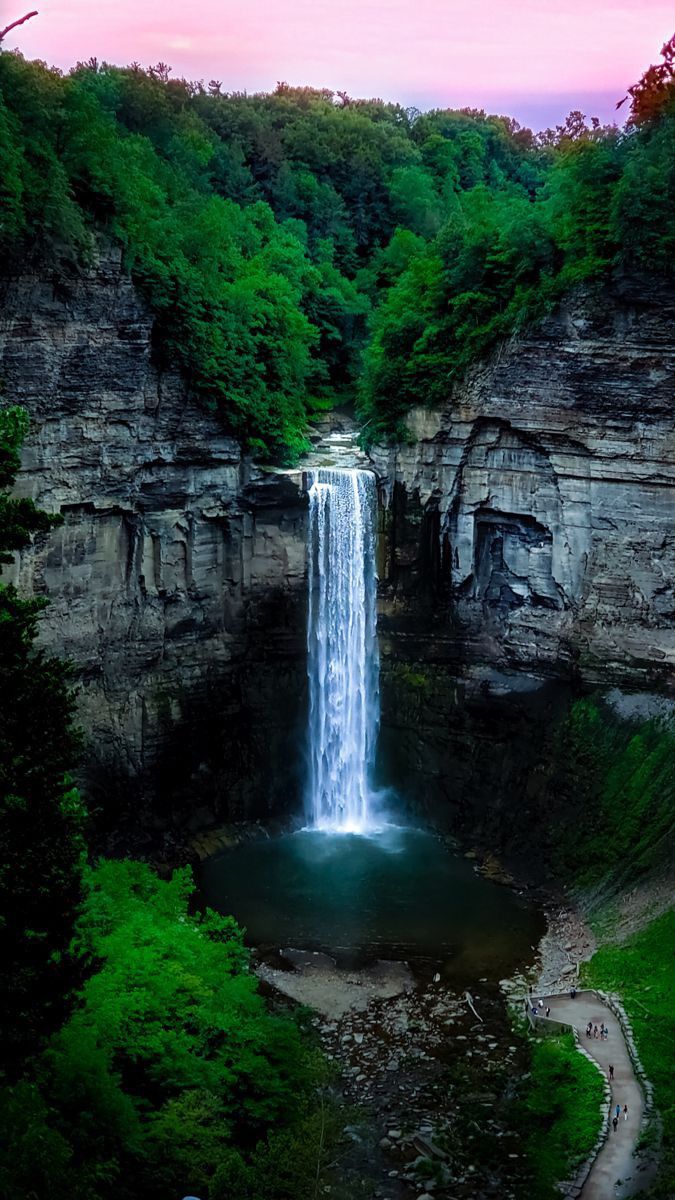 a large waterfall in the middle of a lush green forest