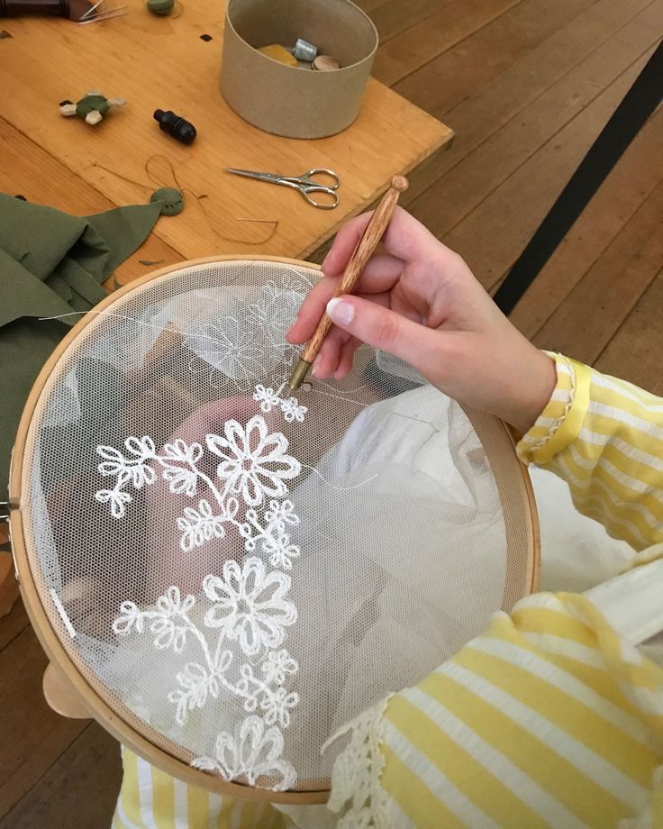 a woman is working on some embroidery