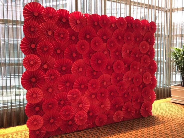 a large red flowered wall in an office building with windows and curtains behind it