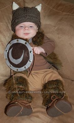 a small child wearing a hat and holding a metal plate with a cat on it