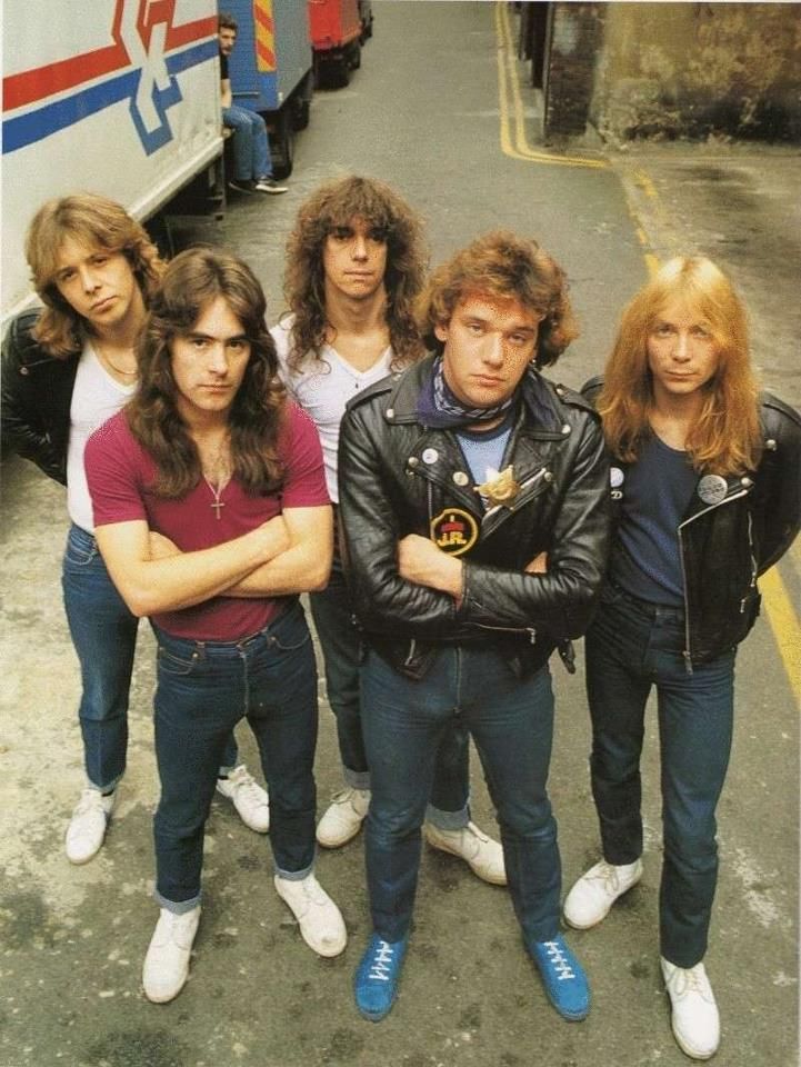 the group of young men are posing for a photo in front of a bus on the street