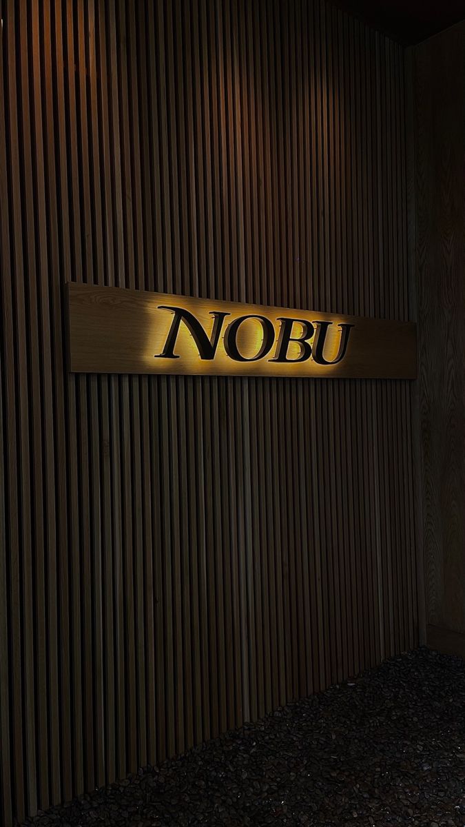 there is a sign that says nobu on the side of a building with wood slats