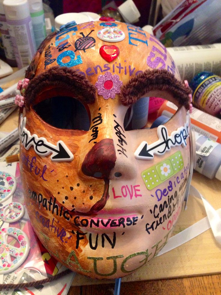 a mask with writing on it sitting on top of a wooden table next to other crafting supplies