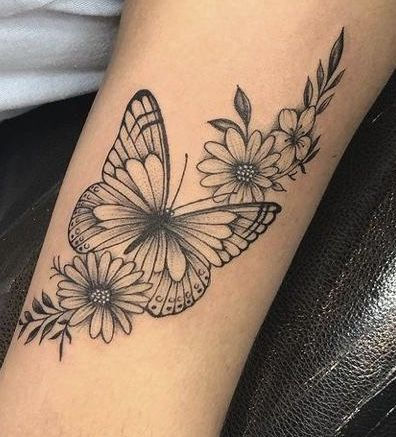 a black and white photo of a butterfly with flowers on it's side arm